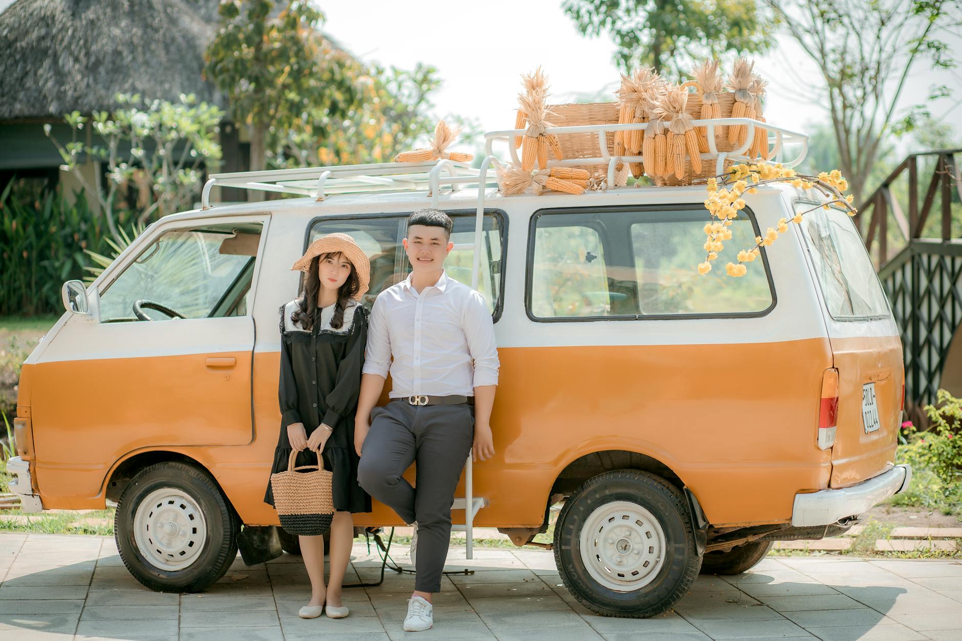 Uśmiechnięta para przy pomarańczowym vanie załadowanym kukurydzą