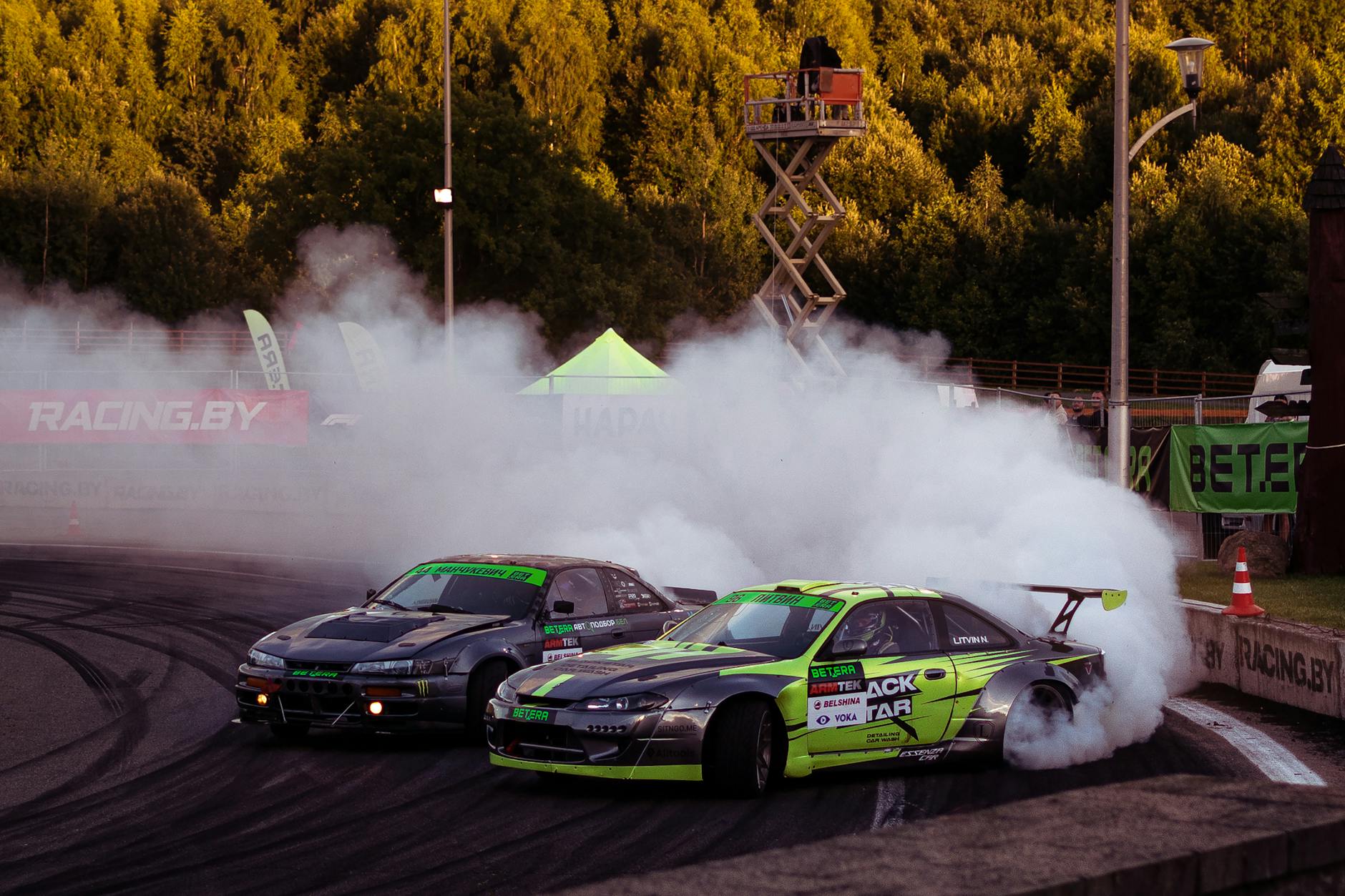 Dwa samochody Nissan S15 jadą bokiem w kłębach dymu podczas driftu