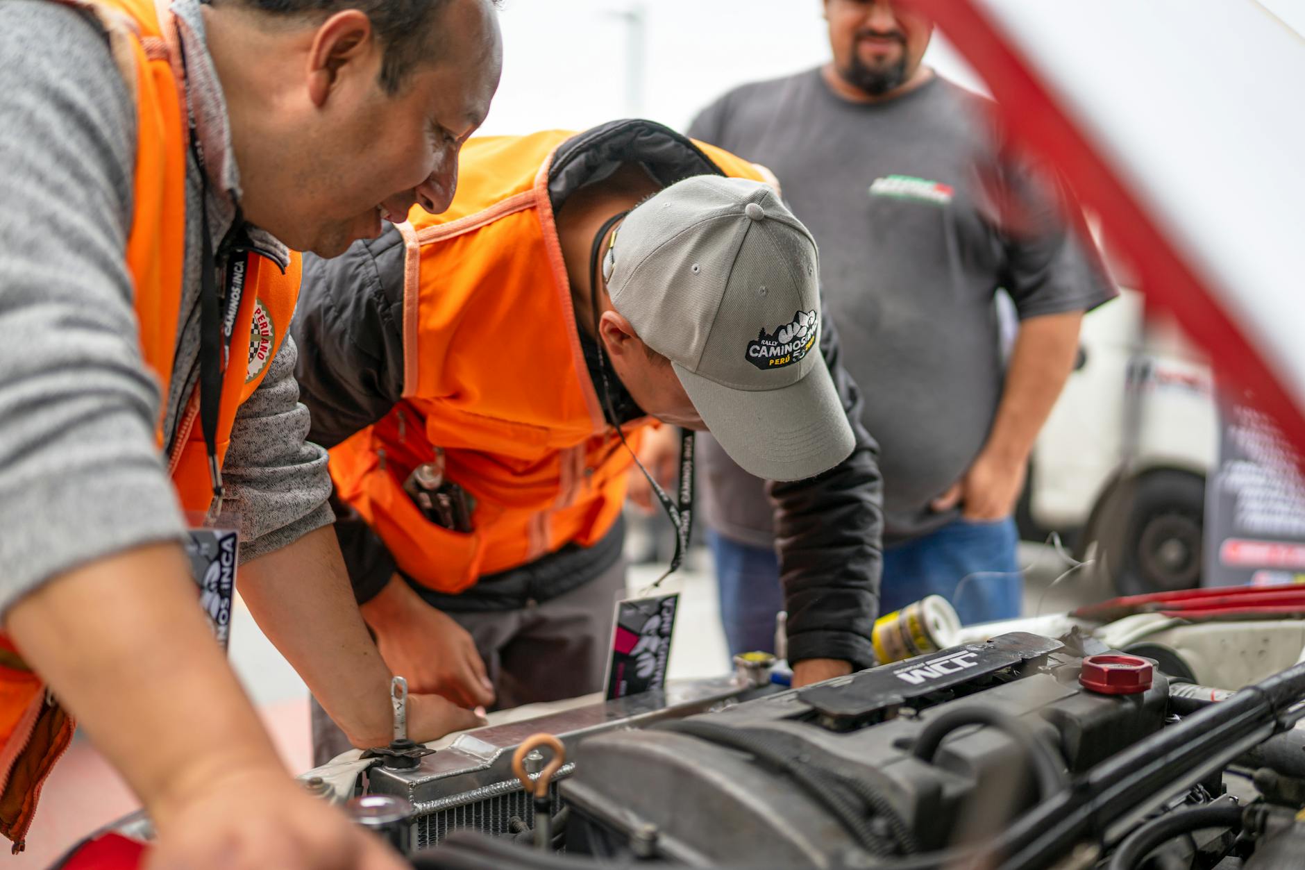 Mechanicy w kamizelkach odblaskowych sprawdzają silnik Cadillaca
