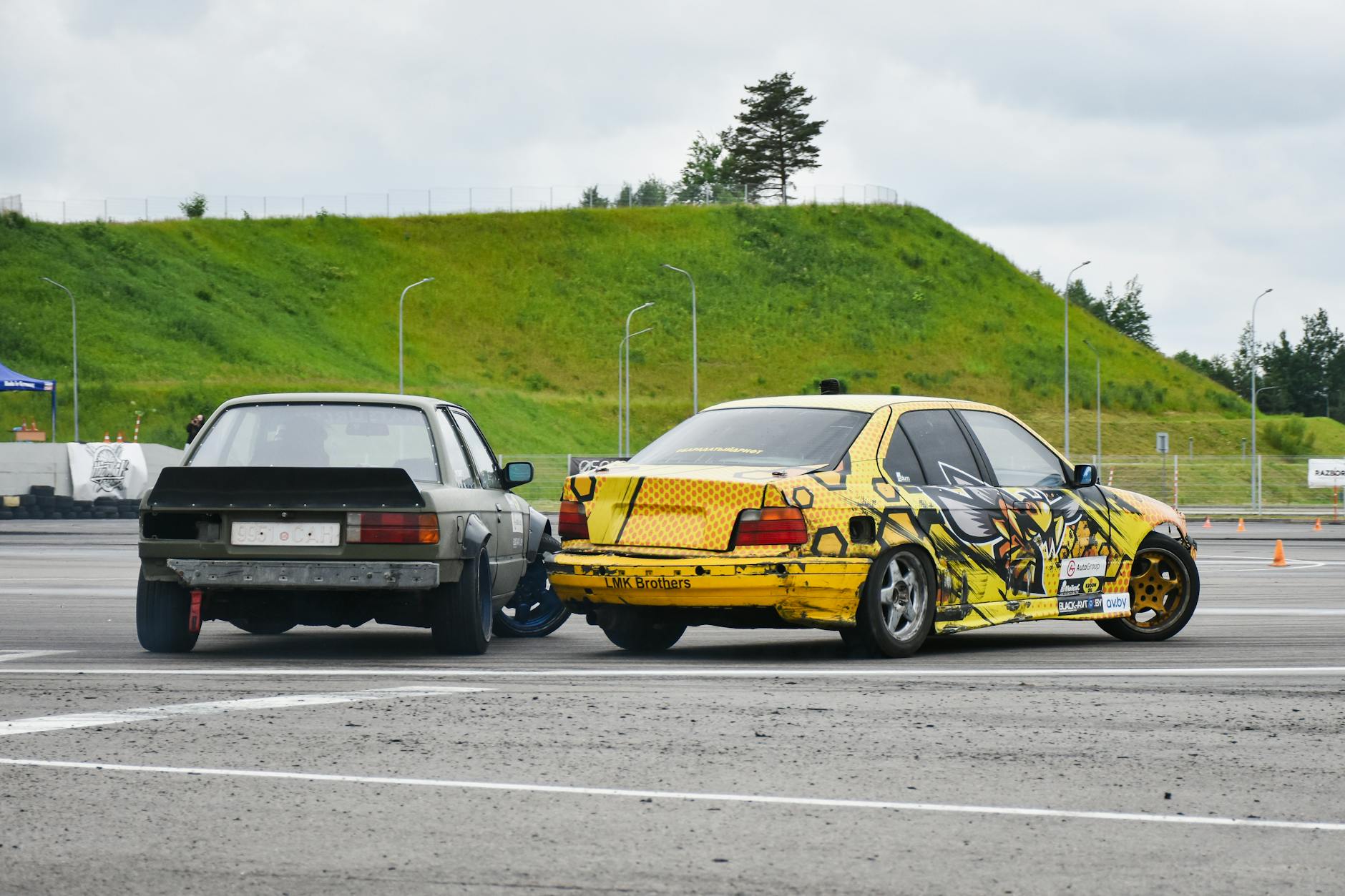 Dwa samochody driftujące na mokrym torze, dynamiczna jazda bokiem