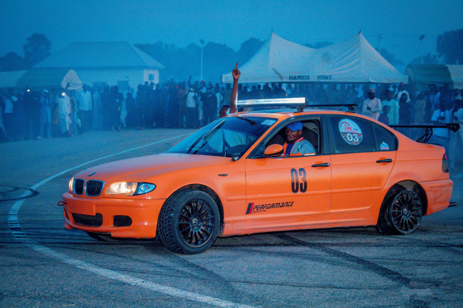 Pomarańczowy Lexus IS200 w drifcie nocą przed podekscytowaną publicznością