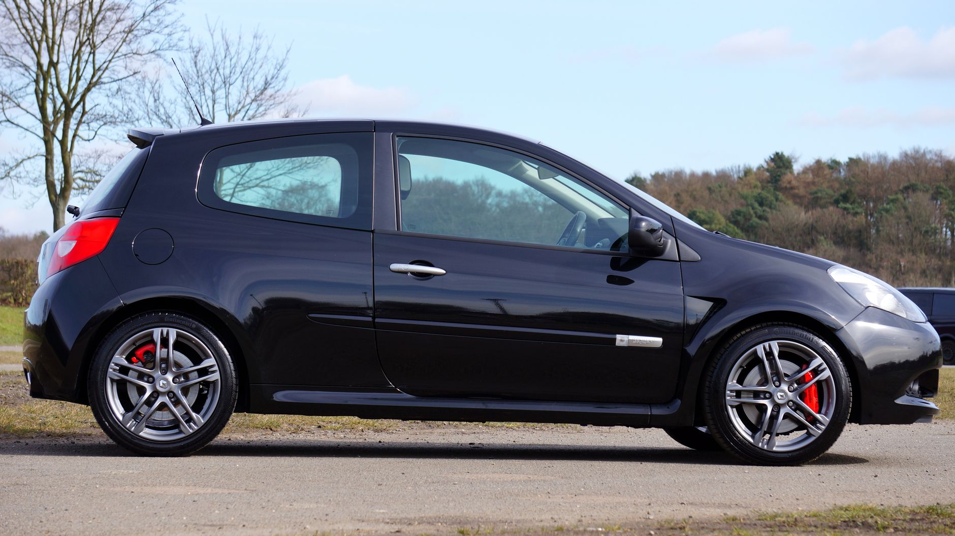 Czarny Renault Clio RS zaparkowany wśród drzew