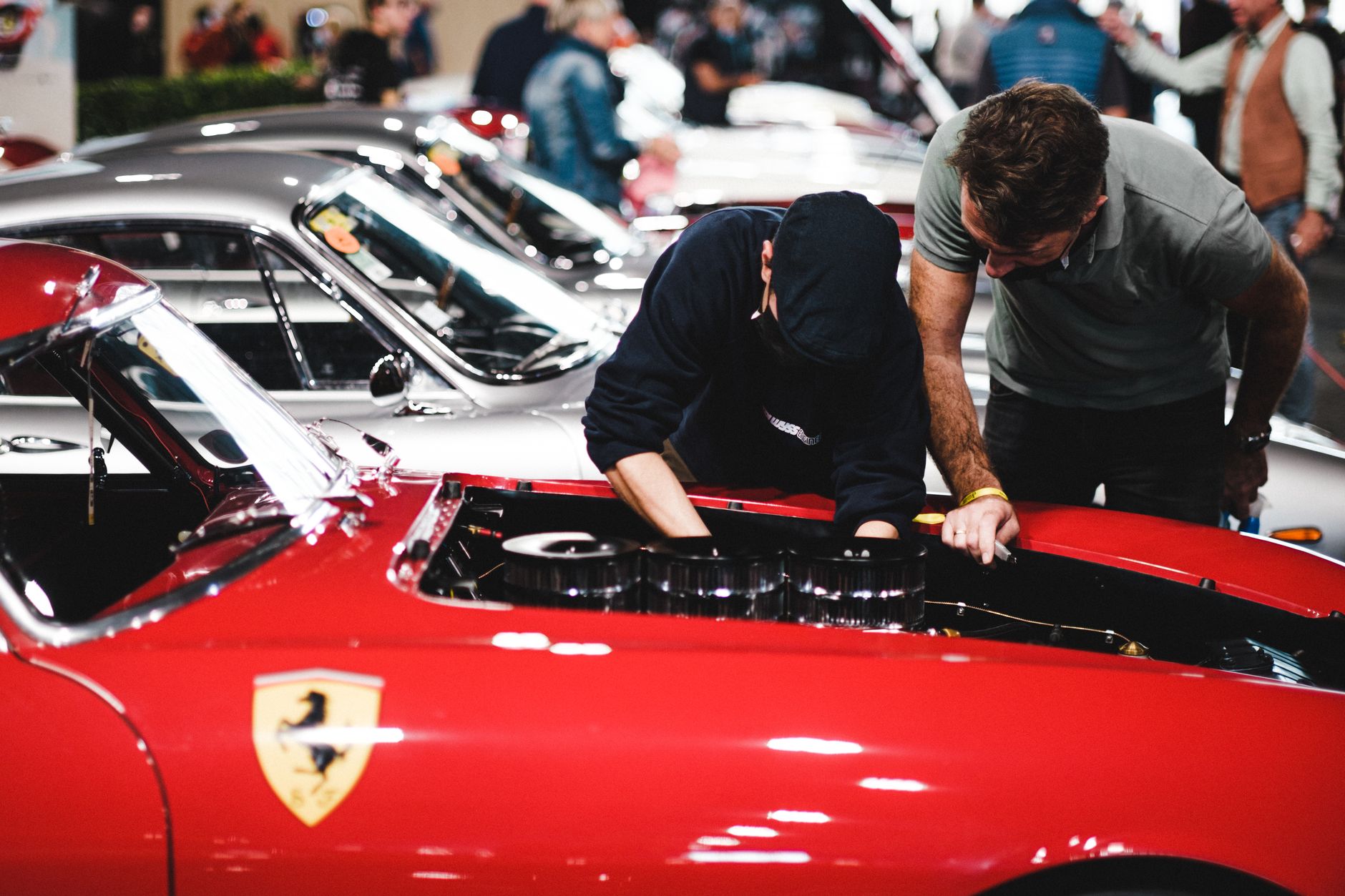 Mechanicy oglądają silnik czerwonego Ferrari na zlocie klasyków