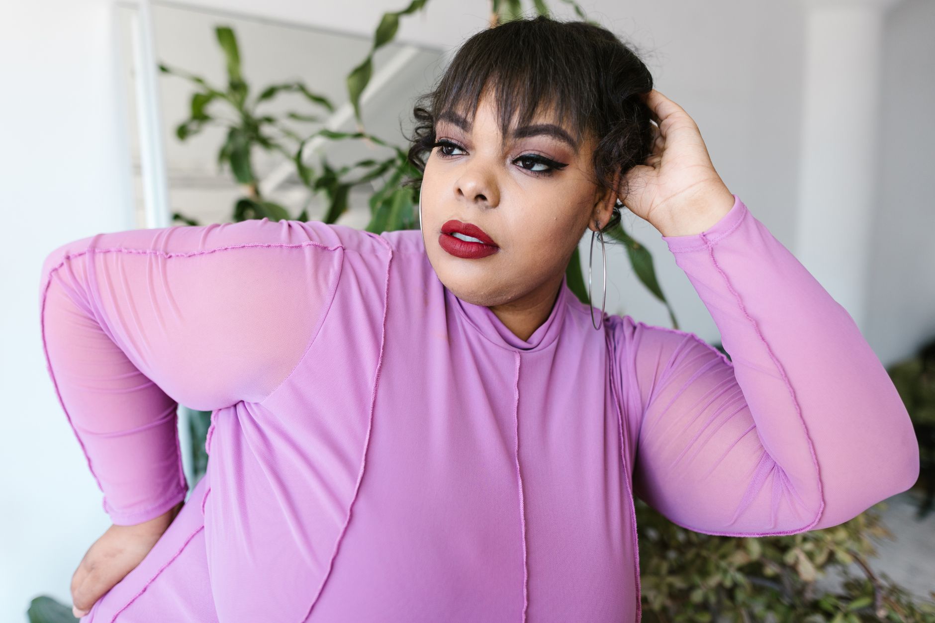 Pewna siebie kobieta plus size w fioletowym stroju dotyka głowy