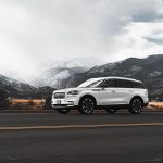 Biały SUV na górskiej drodze w Kolorado z ośnieżonymi szczytami