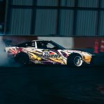 Samochód Mercedes-Benz w drifcie na torze, za nim kłęby dymu